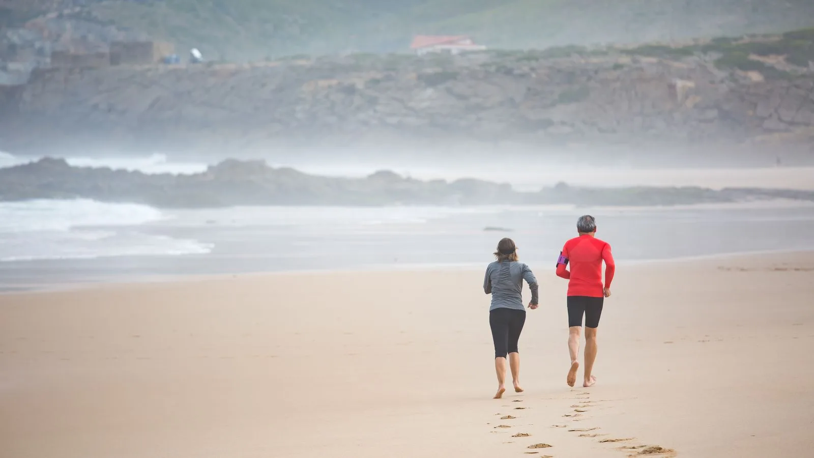 Älteres Paar joggt am Strand